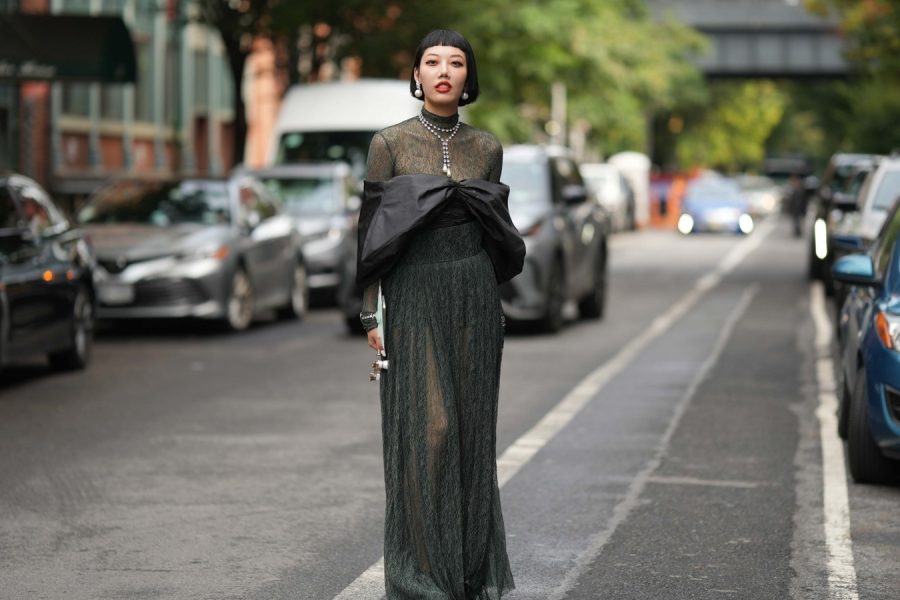 Woman wearing a sheer black blouse paired with high-waisted black trousers and minimal accessories